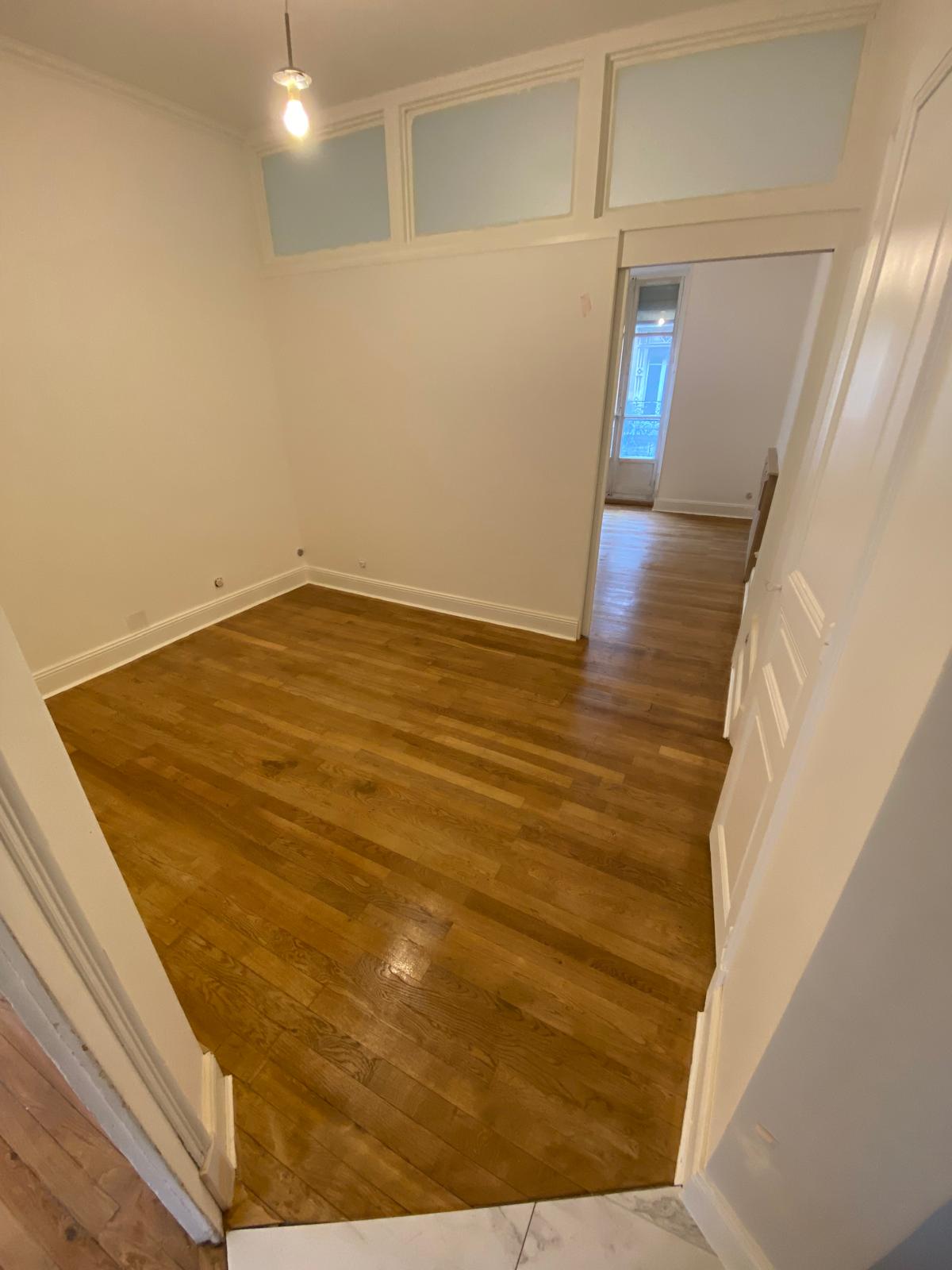 Couloir d'appartement haussmannien avec parquet bois rénové et imposte peinte