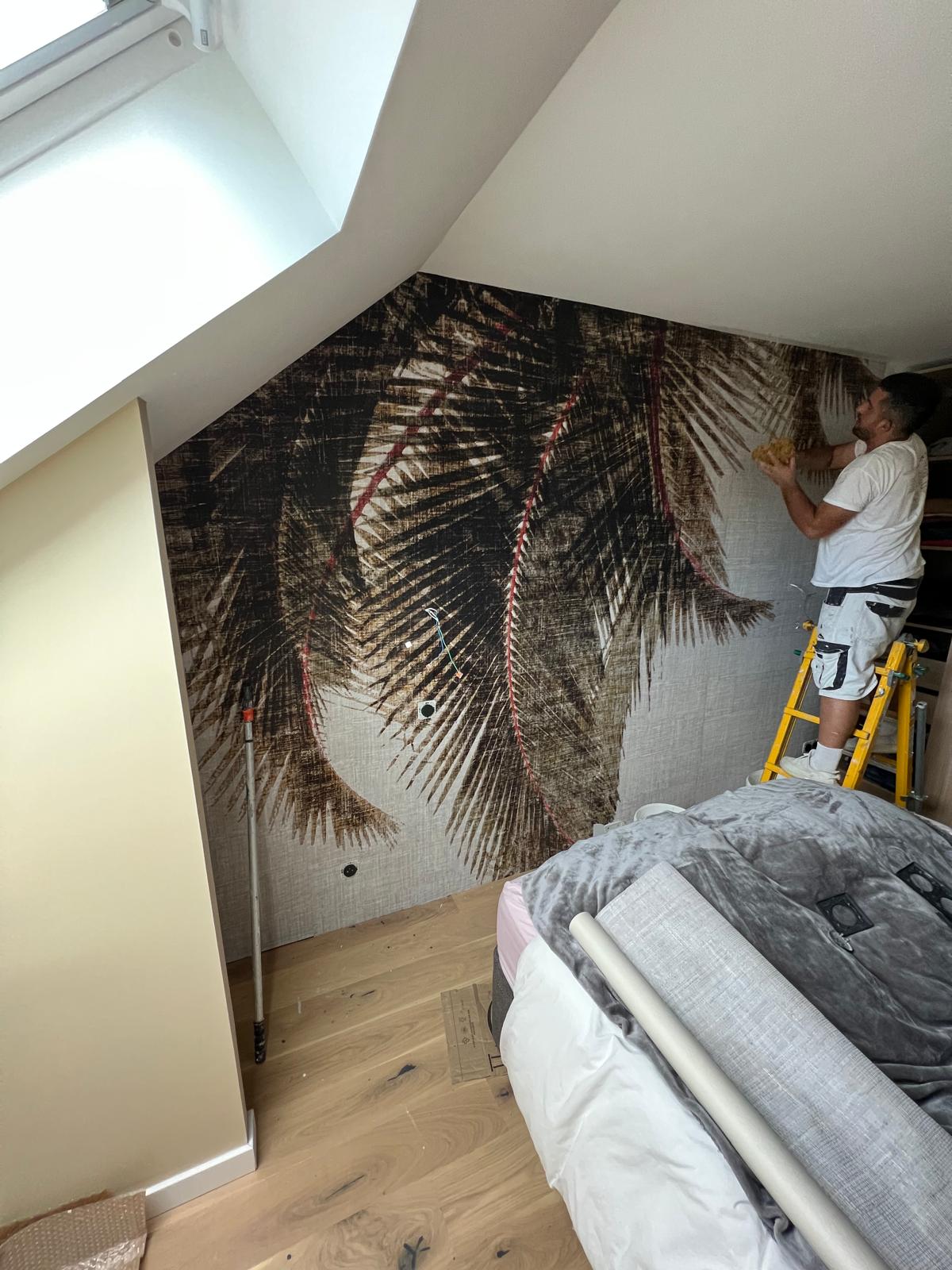 Pose de papier peint panoramique motif palmes dans une chambre sous combles