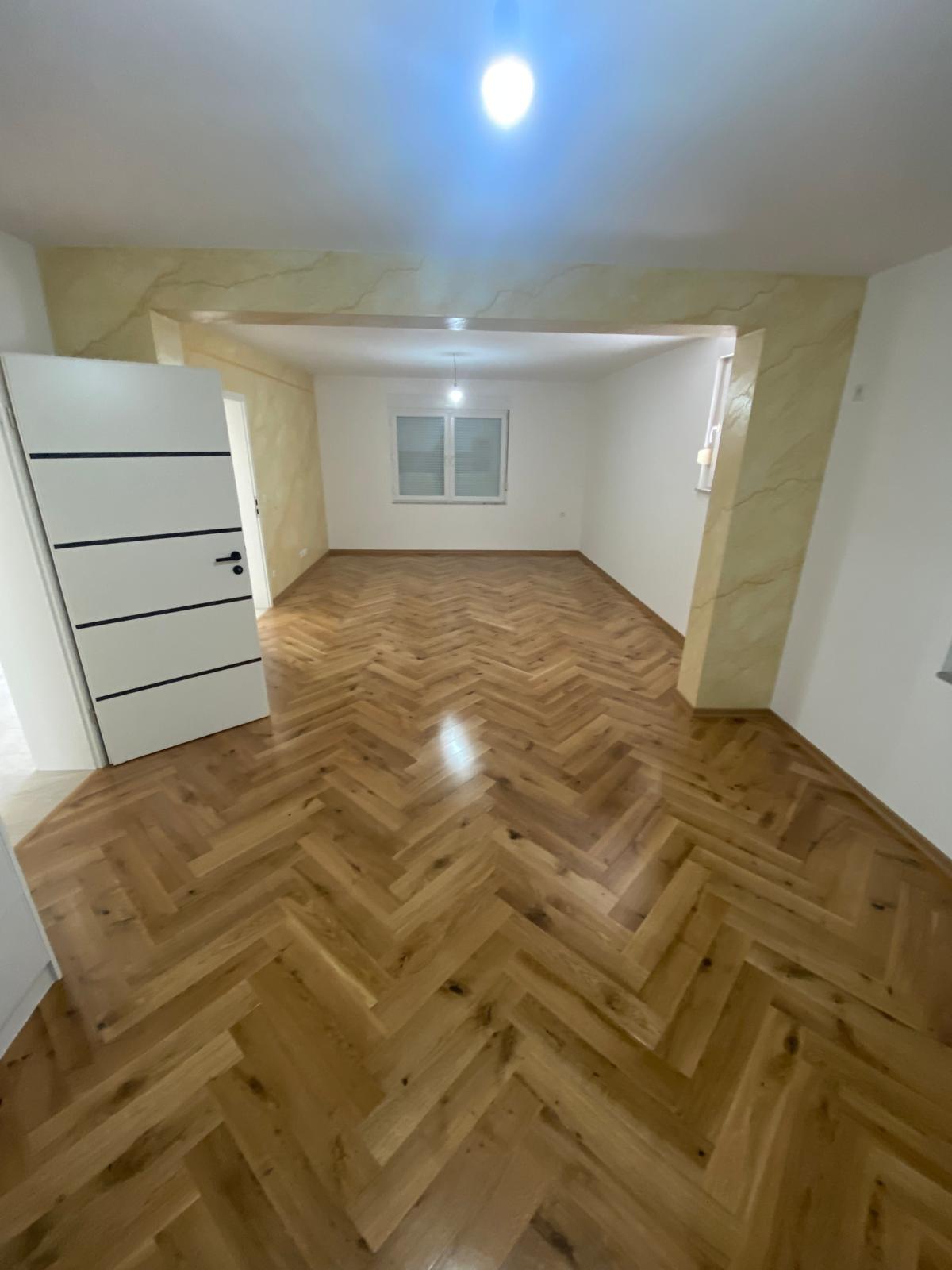 Pièce rénovée avec parquet chevron chêne et bandeau effet marbre beige autour de l'entrée