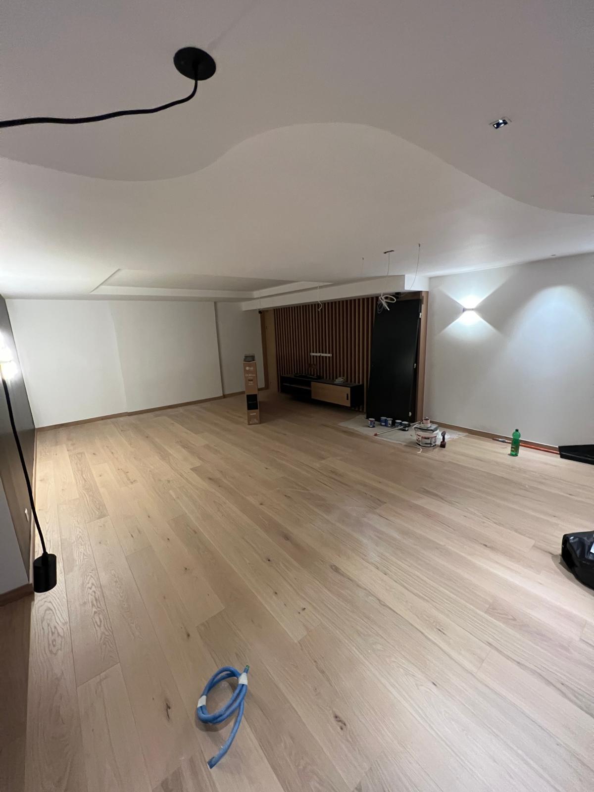 Grand séjour avec parquet chêne clair et faux-plafond en plâtre aux formes courbes