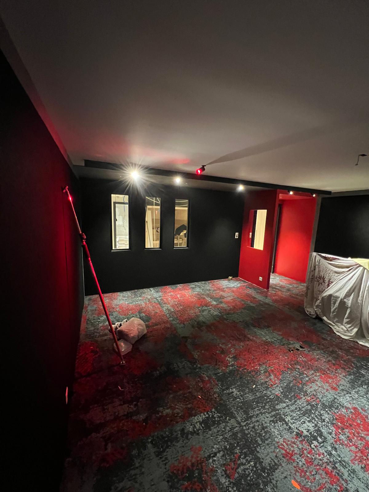 Salle de jeux peinte en noir et rouge avec moquette à motifs et spots encastrés