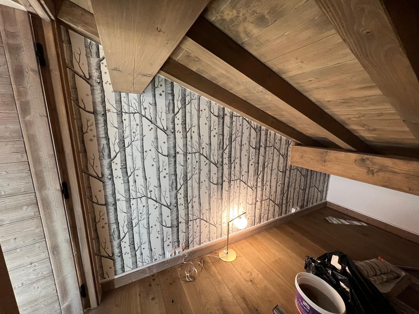 Chambre sous combles d'un chalet avec papier peint motif bouleaux et poutres bois